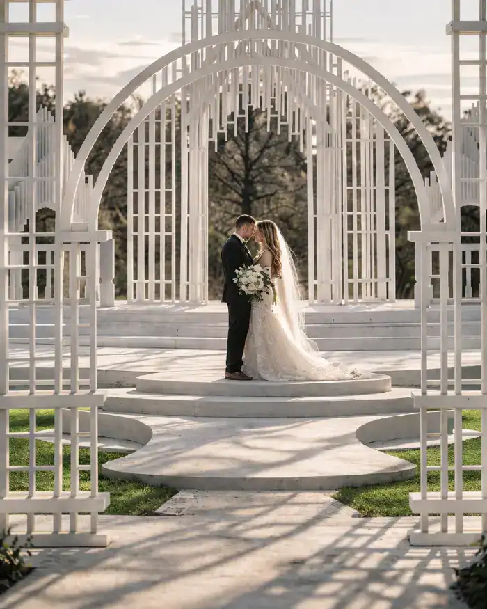 couple kissing at ivory arches wedding ceremony