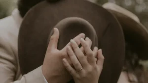 bride and groom kissing behind cowboy hat at outdoor wedding venue near Houston
